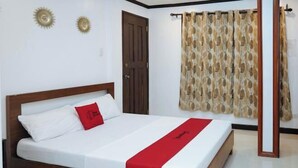 A neatly made bed with a red accent pillow, a wooden headboard, and a white bedspread. - RedDoorz Plus @ Billys Resort Oslob (Oslob)