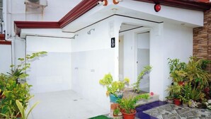 A white building with a red roof, a small entrance, and potted plants around. - RedDoorz Plus @ Billys Resort Oslob (Oslob)