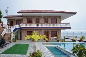 A two-story house with a swimming pool, a balcony, and a view of the sea. - RedDoorz Plus @ Billys Resort Oslob (Oslob)