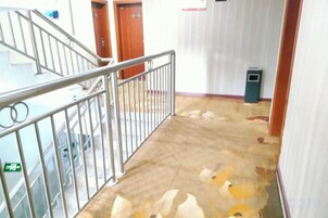 A staircase with metal railings, a wooden door, and a trash bin.