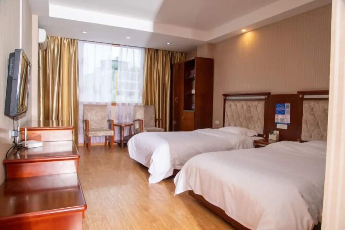 A hotel room with two beds, a desk, a chair, and a television.
