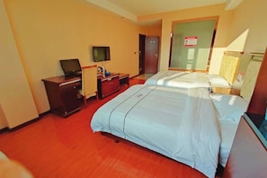 Une chambre d’hôtel avec deux lits, un bureau avec un ordinateur, une télévision et une armoire.