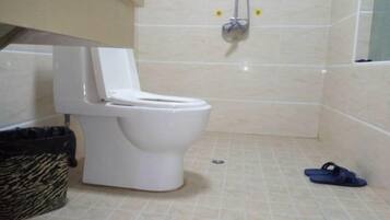 A bathroom with a toilet, a shower, and a tiled floor.