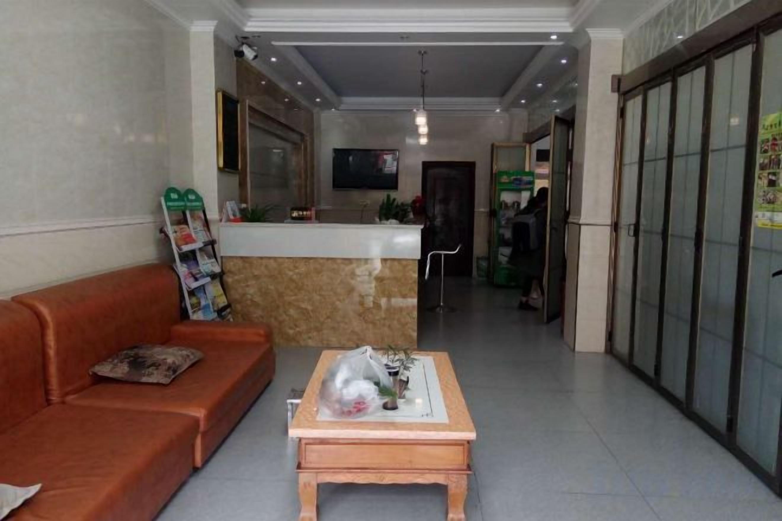 A reception area with a reception desk, a sofa, a coffee table, and a hallway leading to a door.