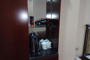 A bathroom with a mirror, a coffee maker, and a bicycle helmet on a shelf.