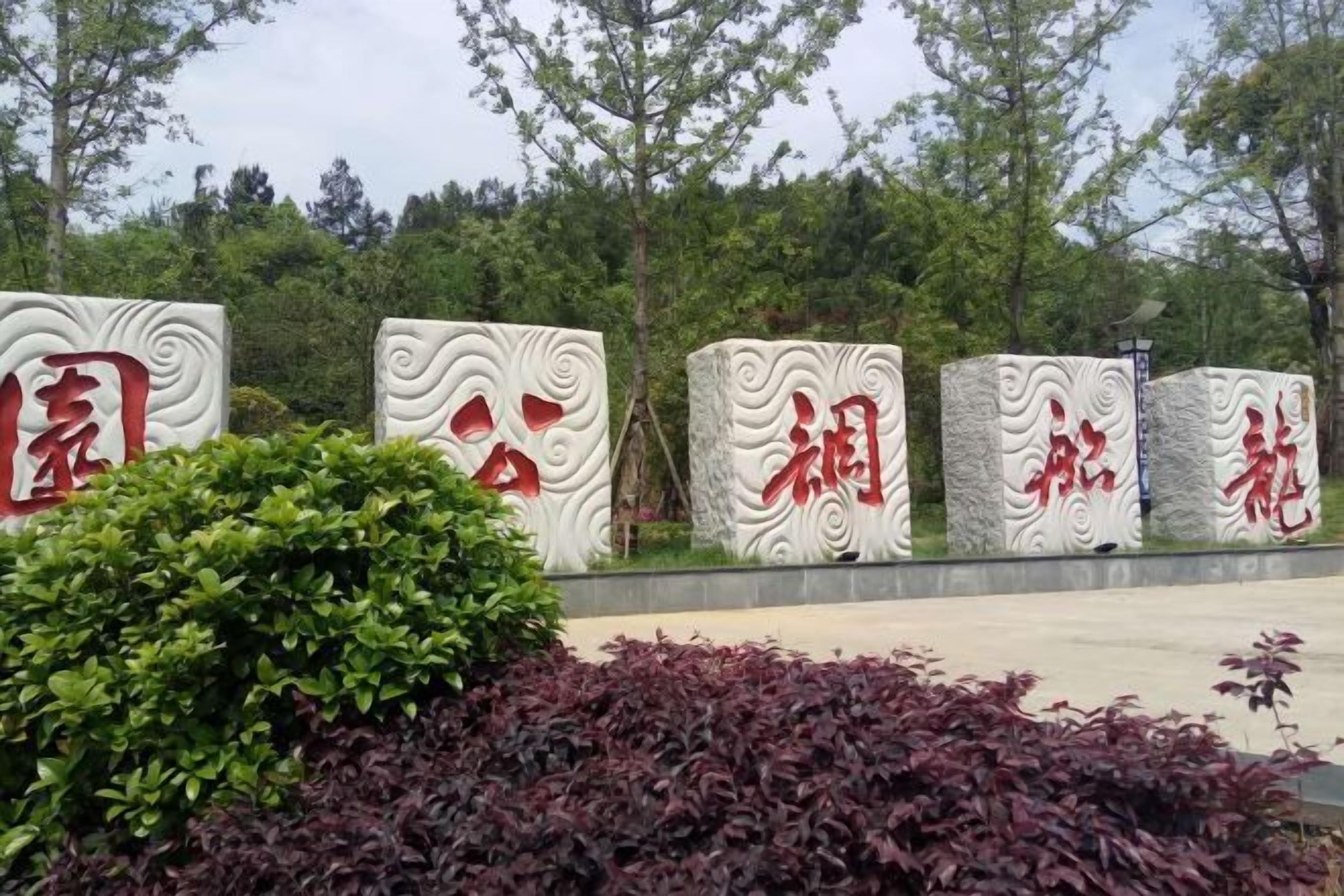 A row of large, white, textured blocks with red Chinese characters, surrounded by greenery.