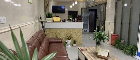 Una zona de recepción con un sofá de cuero, una mesa de madera y plantas en macetas.