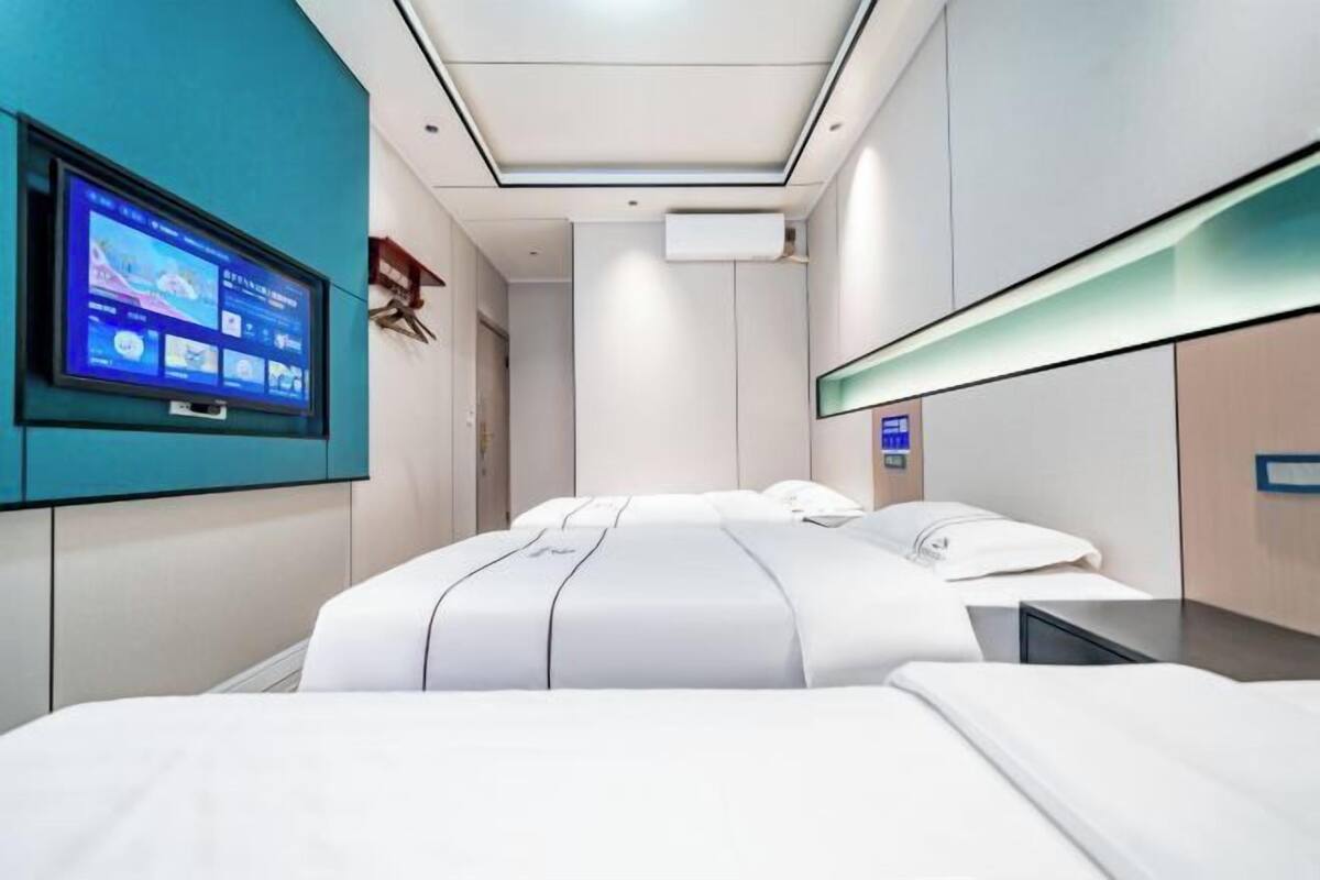 A modern hotel room with a large bed, a flat-screen TV mounted on the wall, and a minimalist design.