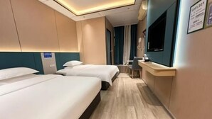 A hotel room with two beds, a desk, a TV, and a sign indicating WiFi availability.