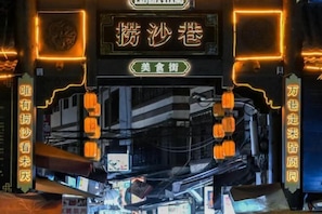 A traditional Chinese architectural entrance with illuminated signs and lanterns.
