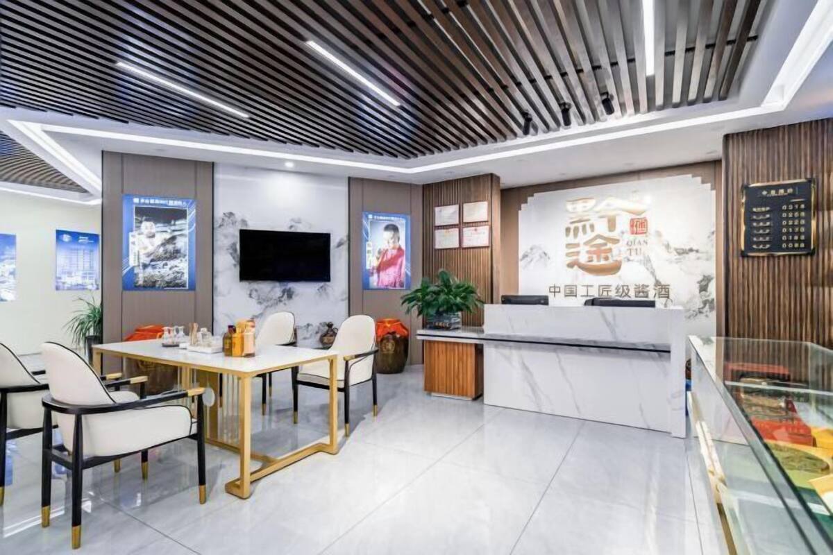 A modern hotel lobby with a reception desk, seating area, and a large screen displaying content.