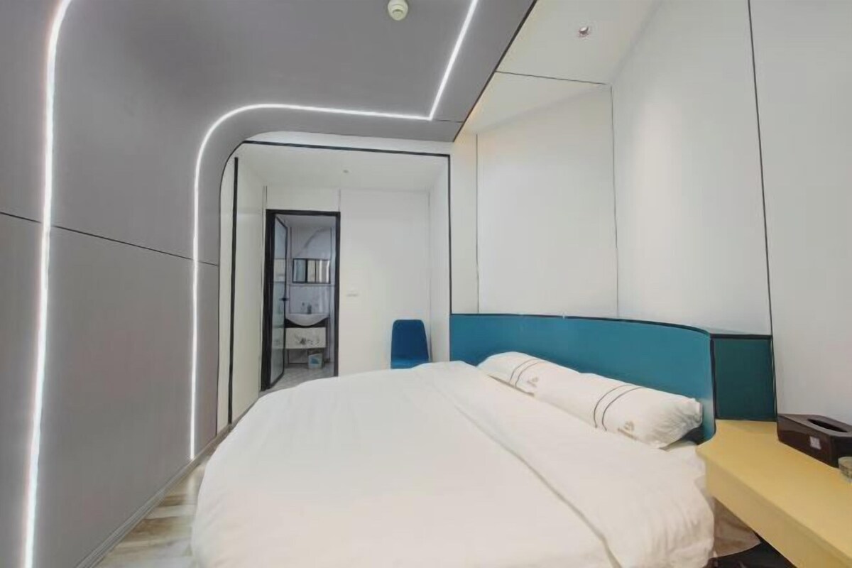 A modern hotel room with a large bed, a bedside table, and a mirror.