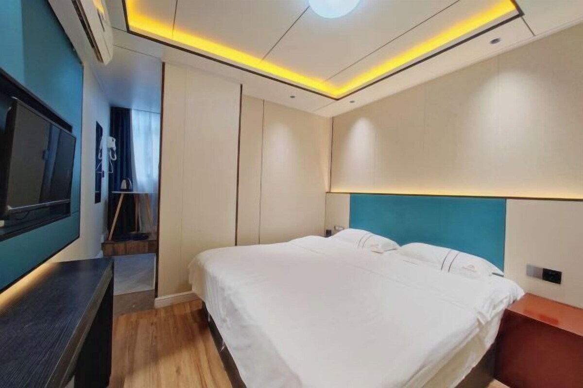 A modern hotel room with a large bed, a TV, and a wooden floor.