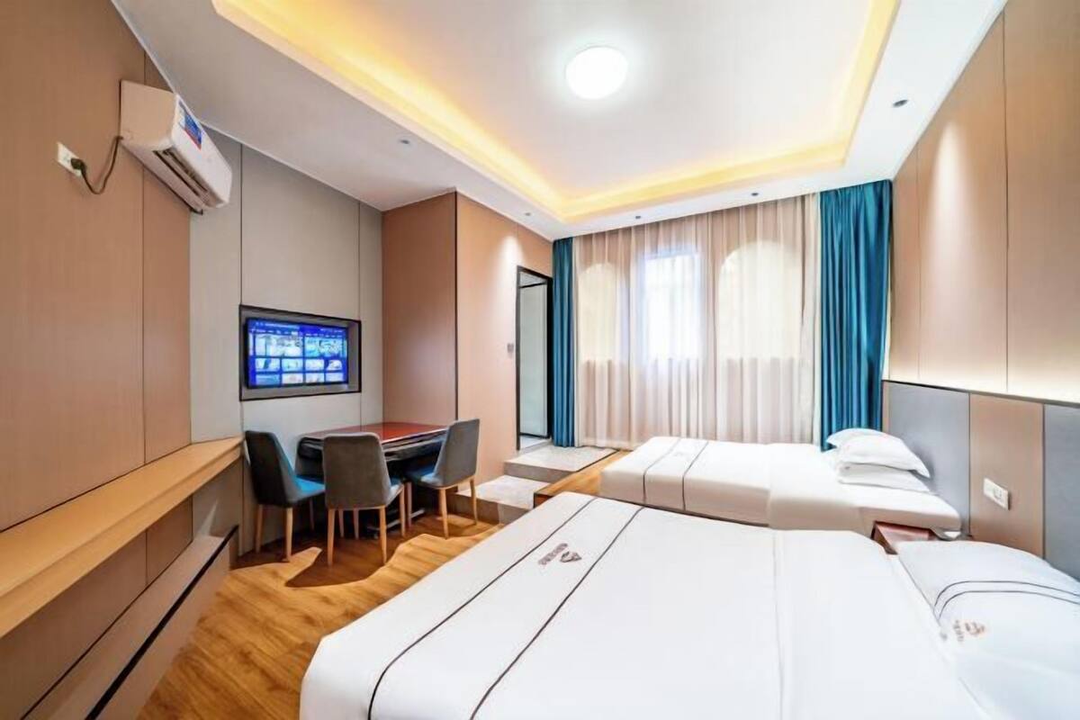 A hotel room with a bed, desk, chairs, and a television.