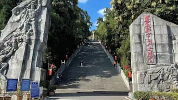 A staircase leading up to a stone monument with inscriptions, surrounded by trees and potted plants.
