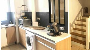 Une cuisine compacte équipée d’un lave-linge, d’un four à micro-ondes, d’un grille-pain et d’une machine à café.