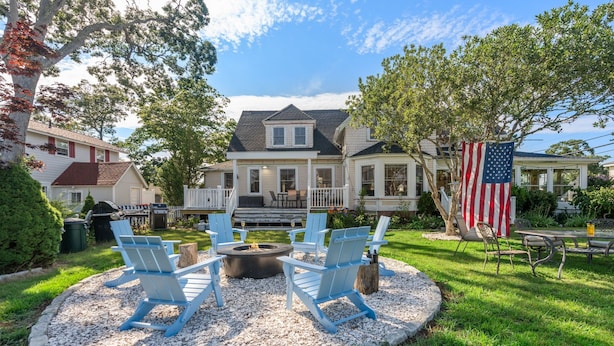 A house with a porch, outdoor seating, and a fire pit. - Onset Oasis_2 min walk to beach, Sleeps 14, HUGE yard w/ lawn games & 2 grills! (Wareham)