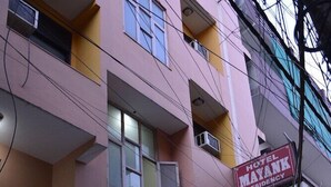 A multi-story building with a sign for 'Hotel Mayank Residency' and a parked white car in front.