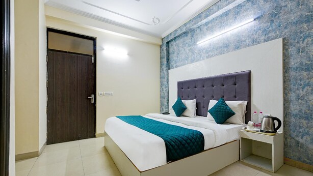 A hotel room with a bed, a nightstand, a door, and a wall with a textured pattern.