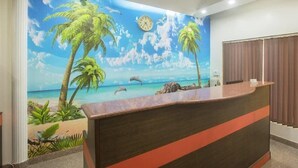 A reception area with a mural of a beach scene, a reception desk, and a ceiling fan.