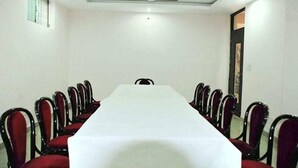 A conference room with a long table, red upholstered chairs, a ceiling fan, and a window on the left wall.