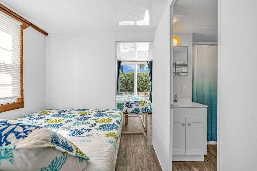 Una habitación compacta con dos camas, un baño pequeño y vistas al exterior.