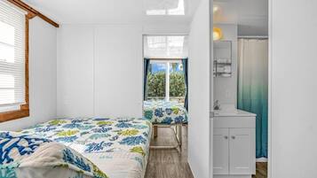 Una habitación compacta con dos camas, un baño pequeño y vistas al exterior.