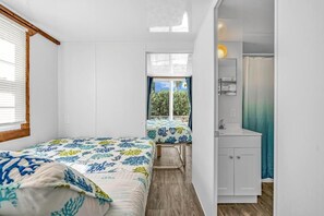Una habitación compacta con dos camas, un baño pequeño y vistas al exterior.