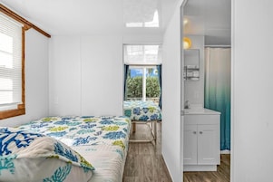 Una habitación compacta con dos camas, un baño pequeño y vistas al exterior.