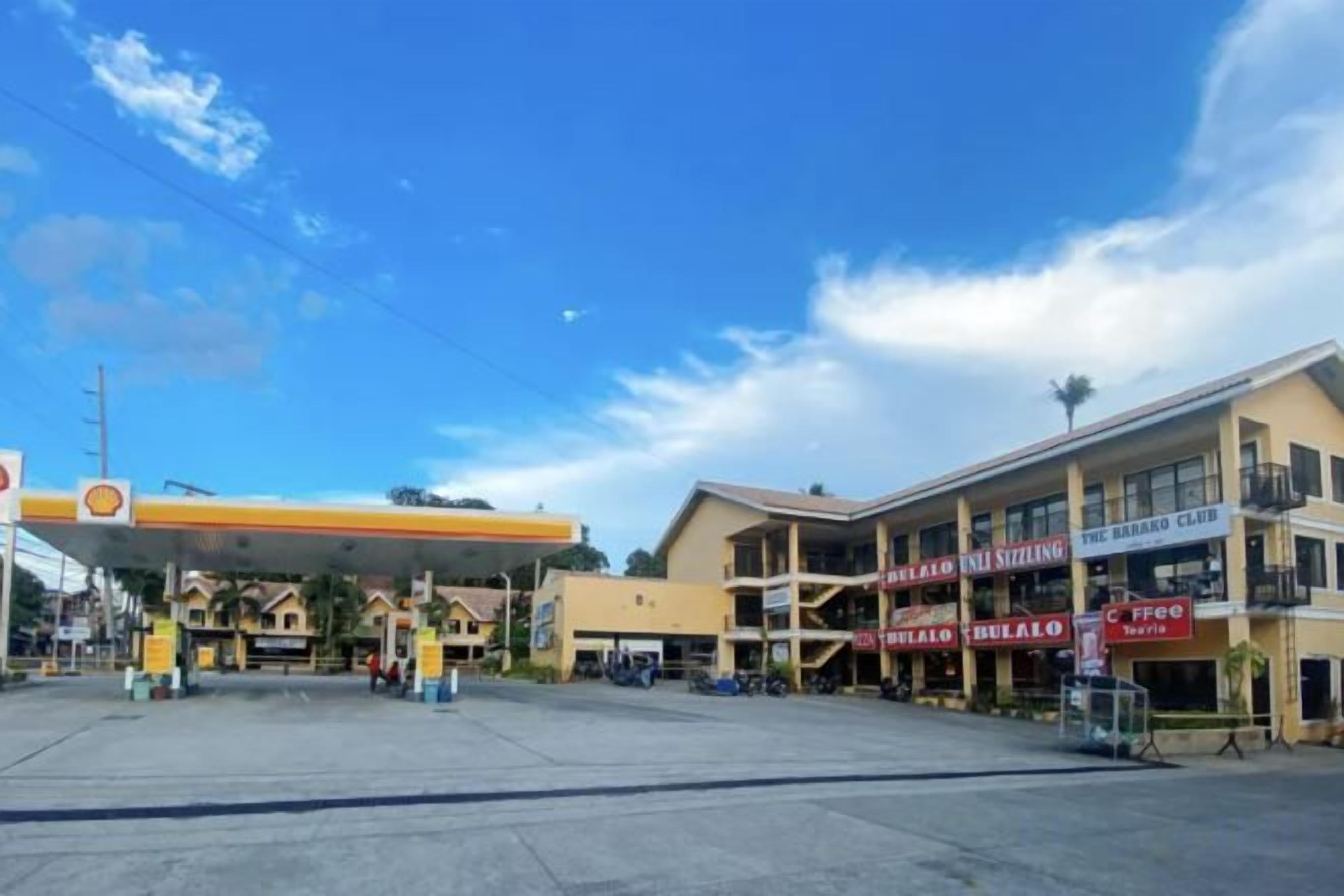 A gas station with a Shell sign, a building with a sign for 'The 360 Club', and a coffee shop named 'Café'.
