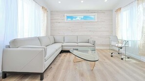A modern living room with a sectional sofa, a glass coffee table, and a desk with a chair. - Marvelous Margate family abode (Margate City)