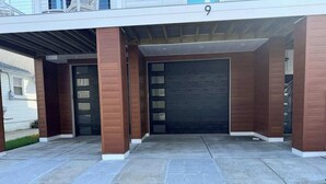 A modern building entrance with a covered driveway, a garage door, and a number '9' sign. - Marvelous Margate family abode (Margate City)