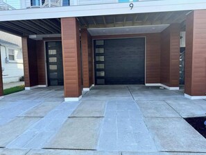 Moderne entree met overdekte oprit, garagepoort en nummer '9'.