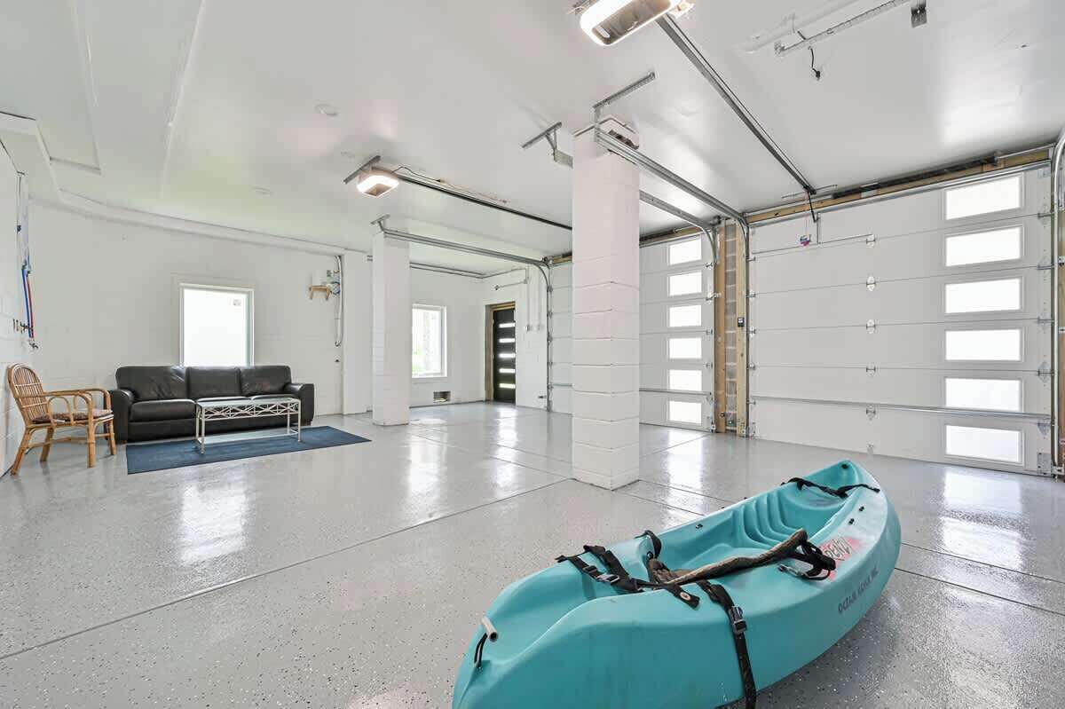 Une pièce spacieuse avec une grande fenêtre, un canapé, un fauteuil et un kayak.