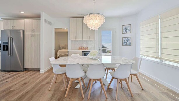 A modern kitchen with a marble island, white cabinetry, and a stainless steel refrigerator. - Marvelous Margate family abode (Margate City)