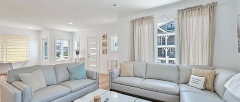 A modern living room with two sofas, a coffee table, and a view of a building through large windows.