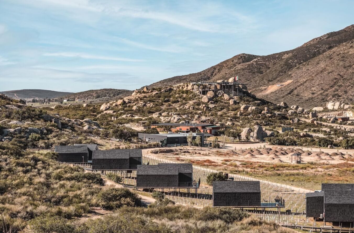 A desert landscape with a prominent building on a hill, surrounded by rocky terrain and sparse vegetation.
