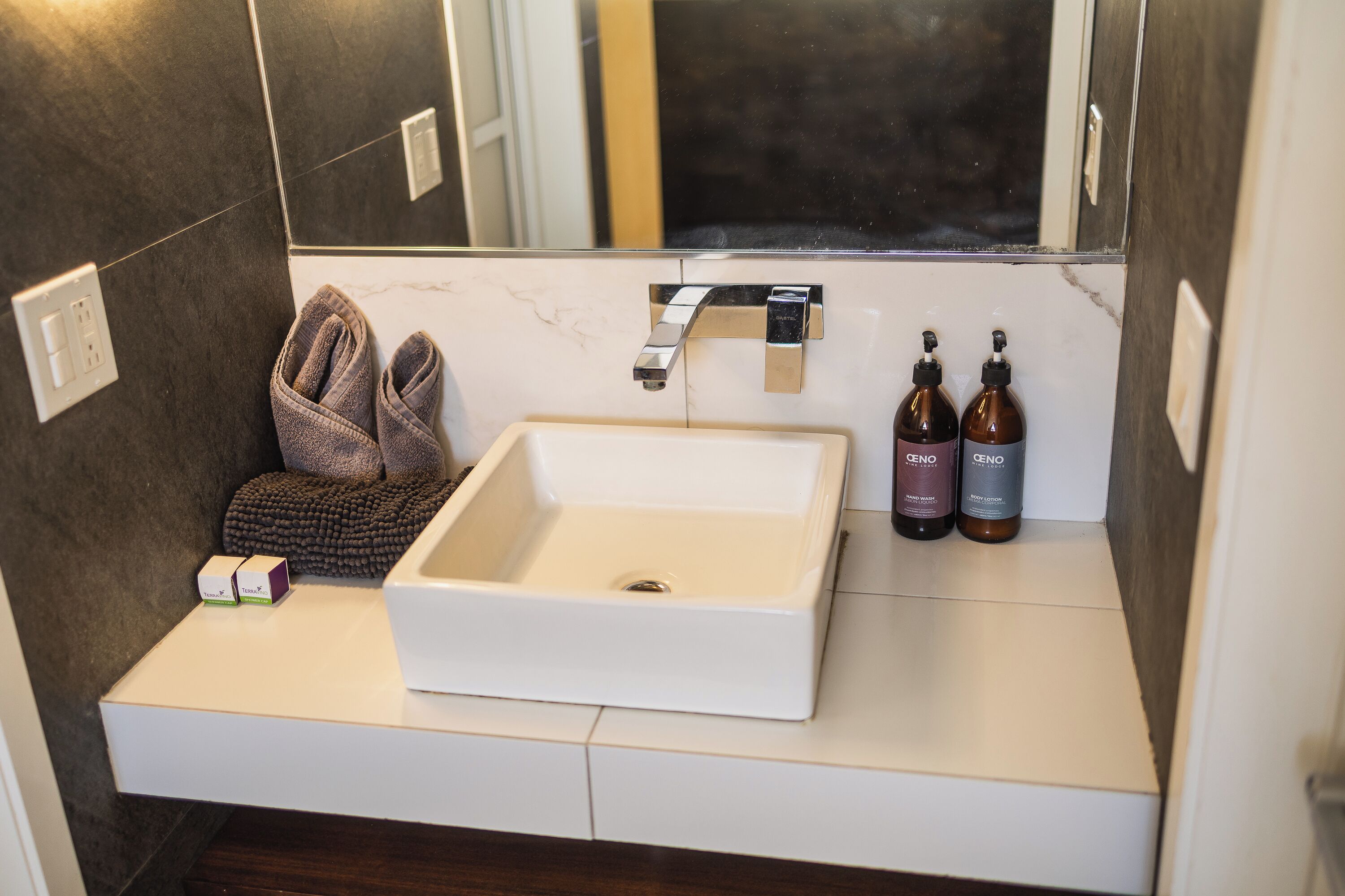 A bathroom with a white sink, a towel, and two bottles of CENO soap.