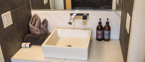 A bathroom with a white sink, a towel, and two bottles of CENO soap.