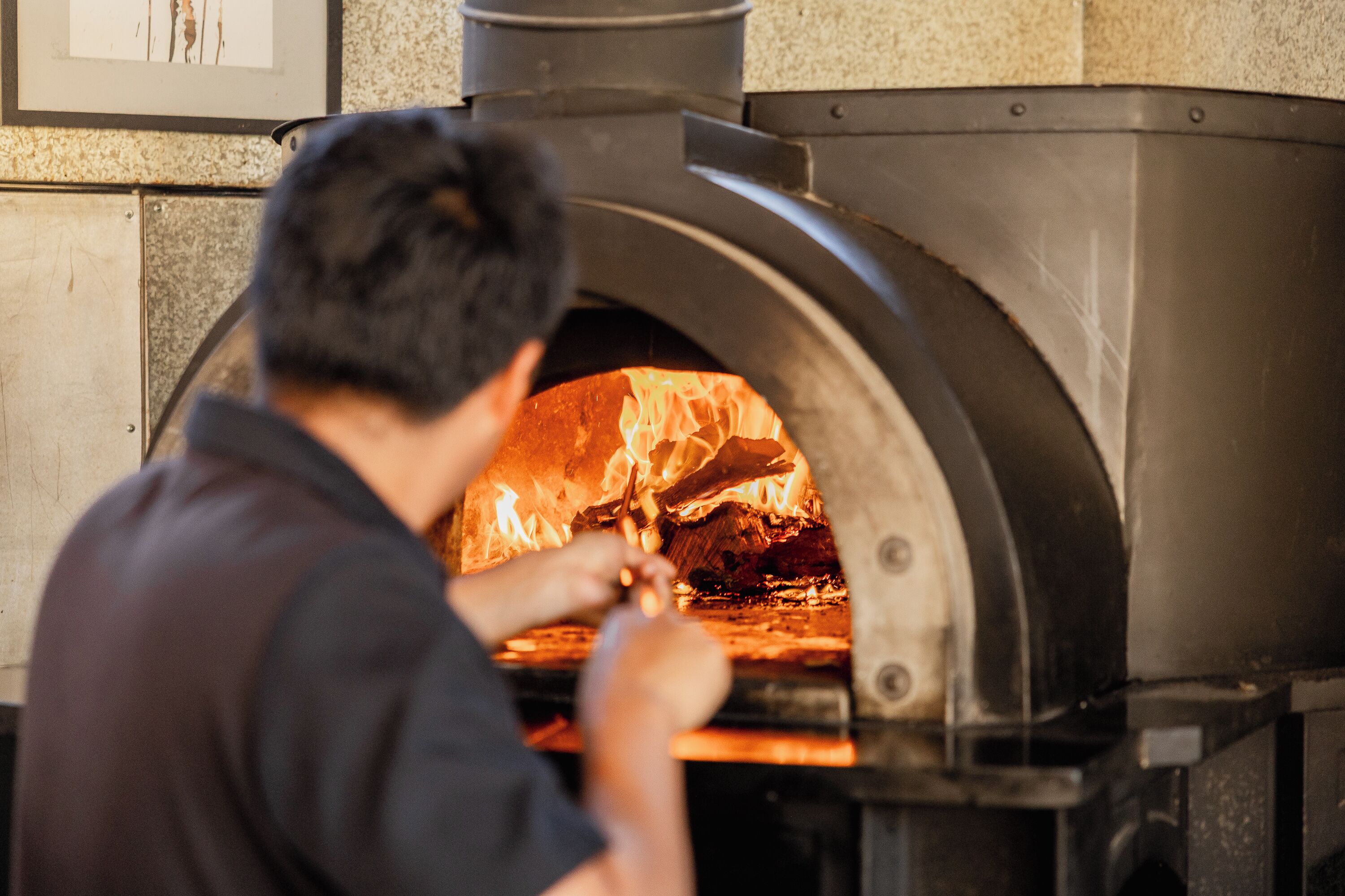 Une personne qui ouvre la porte d’un four à pizza.