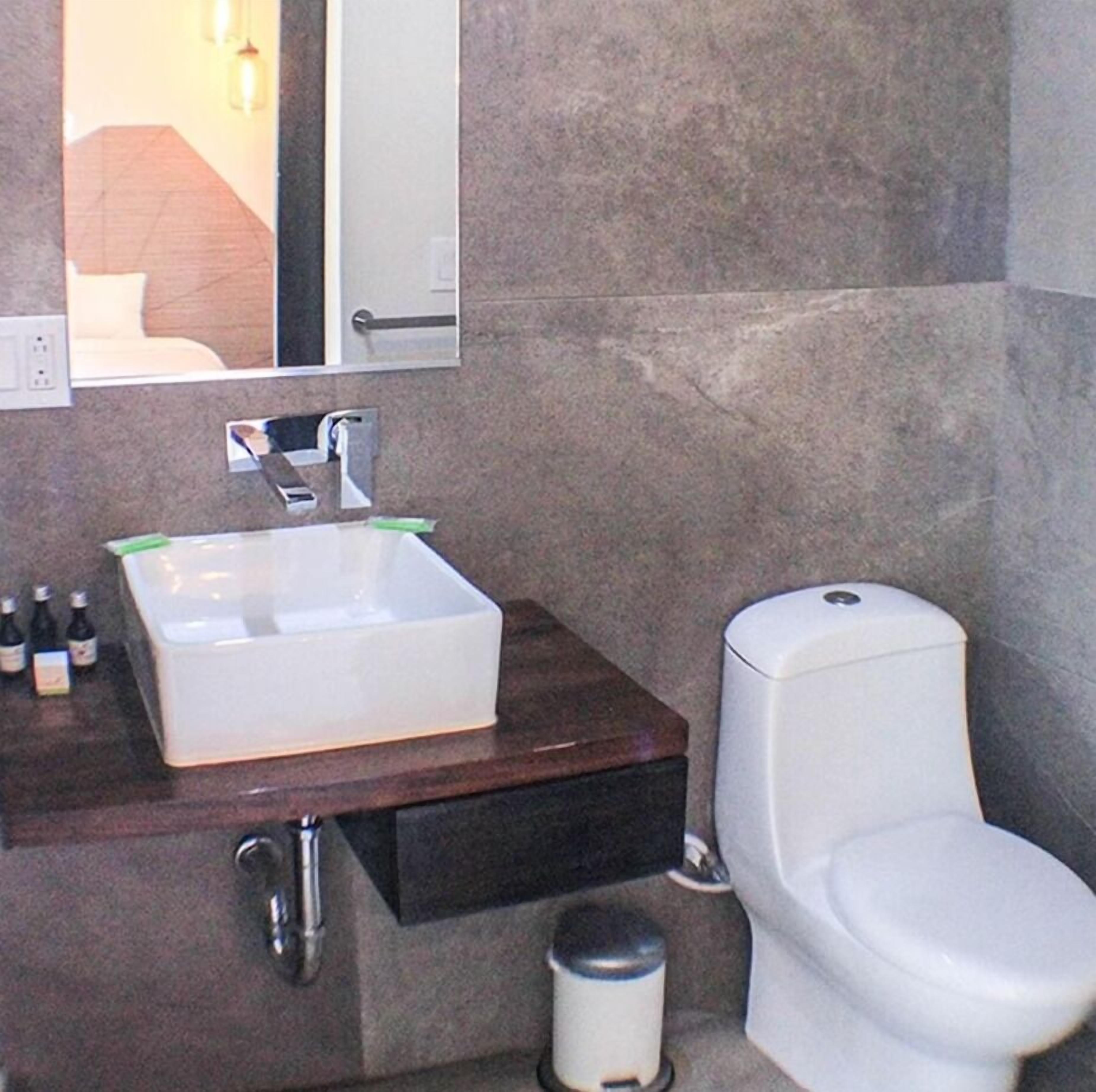 A bathroom with a white sink, a mirror, and a toilet.