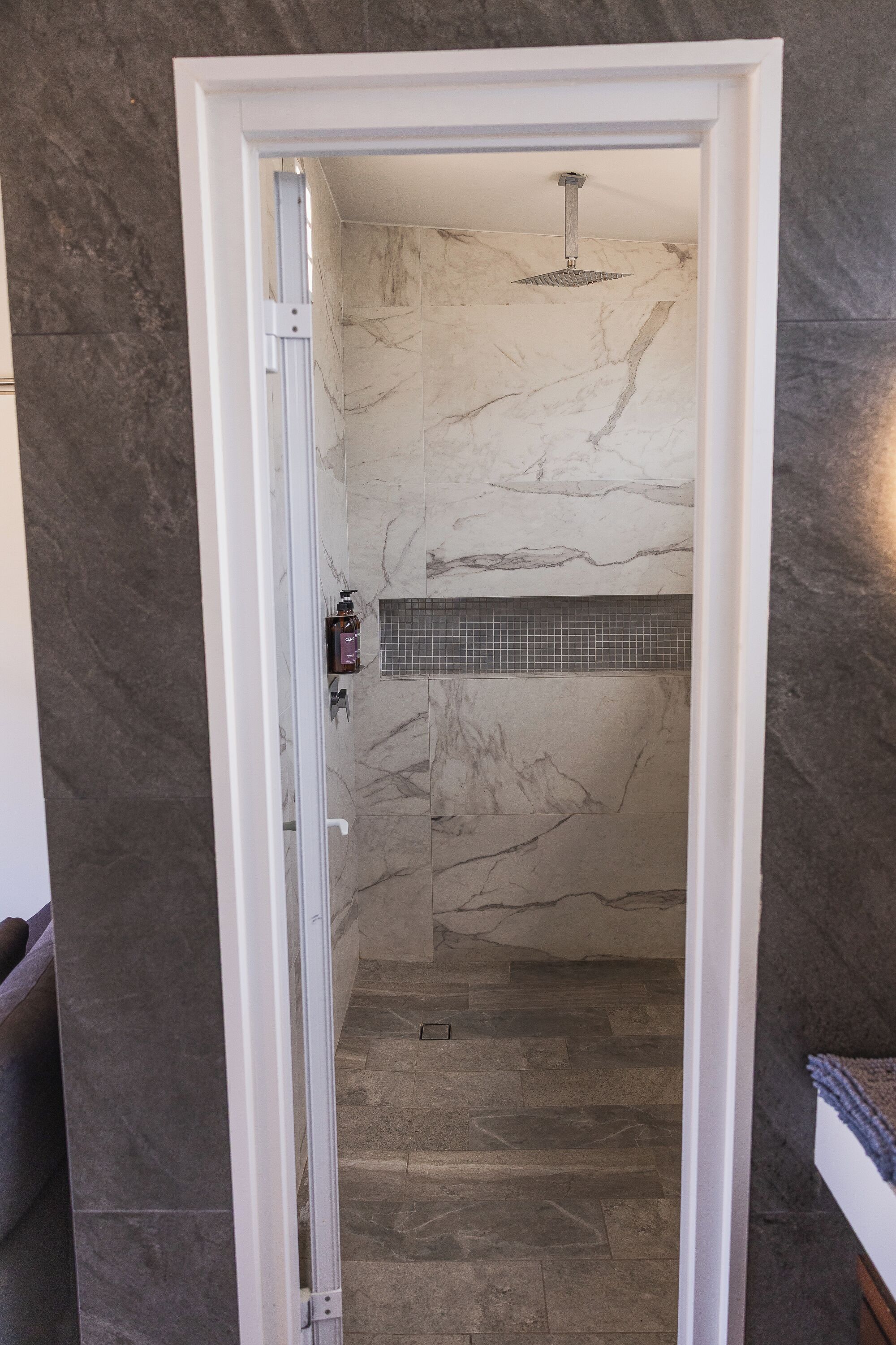 A bathroom with marble walls and a shower area.