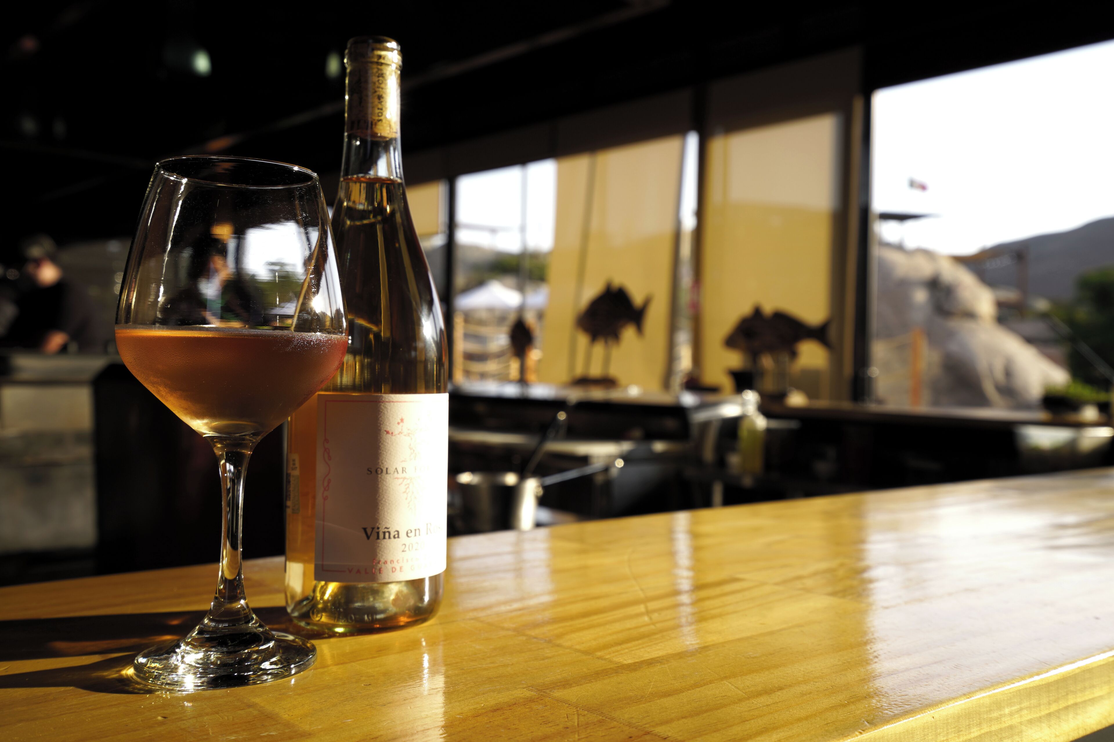 Una copa de vino y una botella sobre una barra de madera.