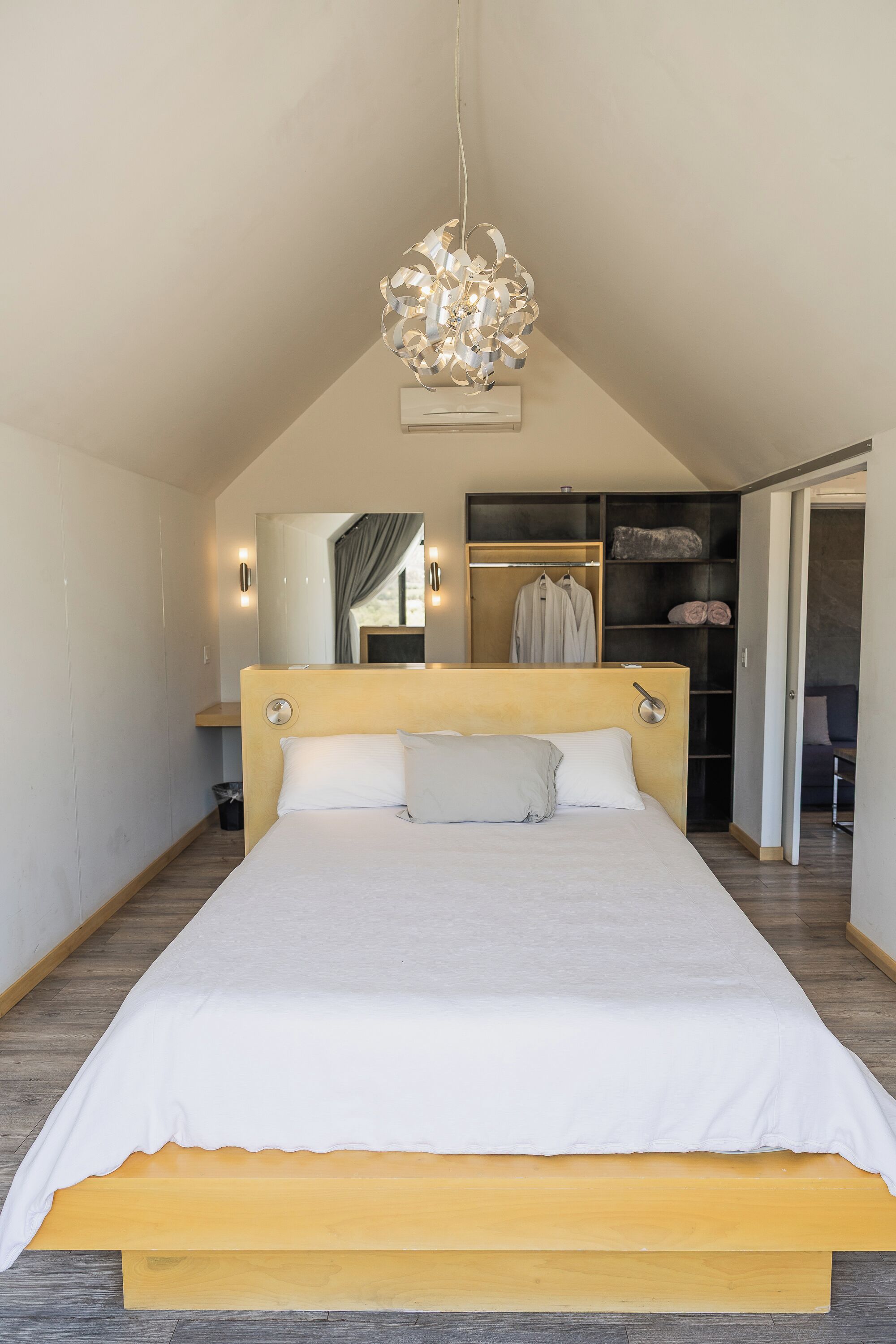 Un dormitorio moderno con una cama grande, cabecera de madera, armario empotrado y lámpara en el techo.