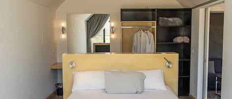 Un dormitorio moderno con una cama grande, cabecera de madera, armario empotrado y lámpara en el techo.