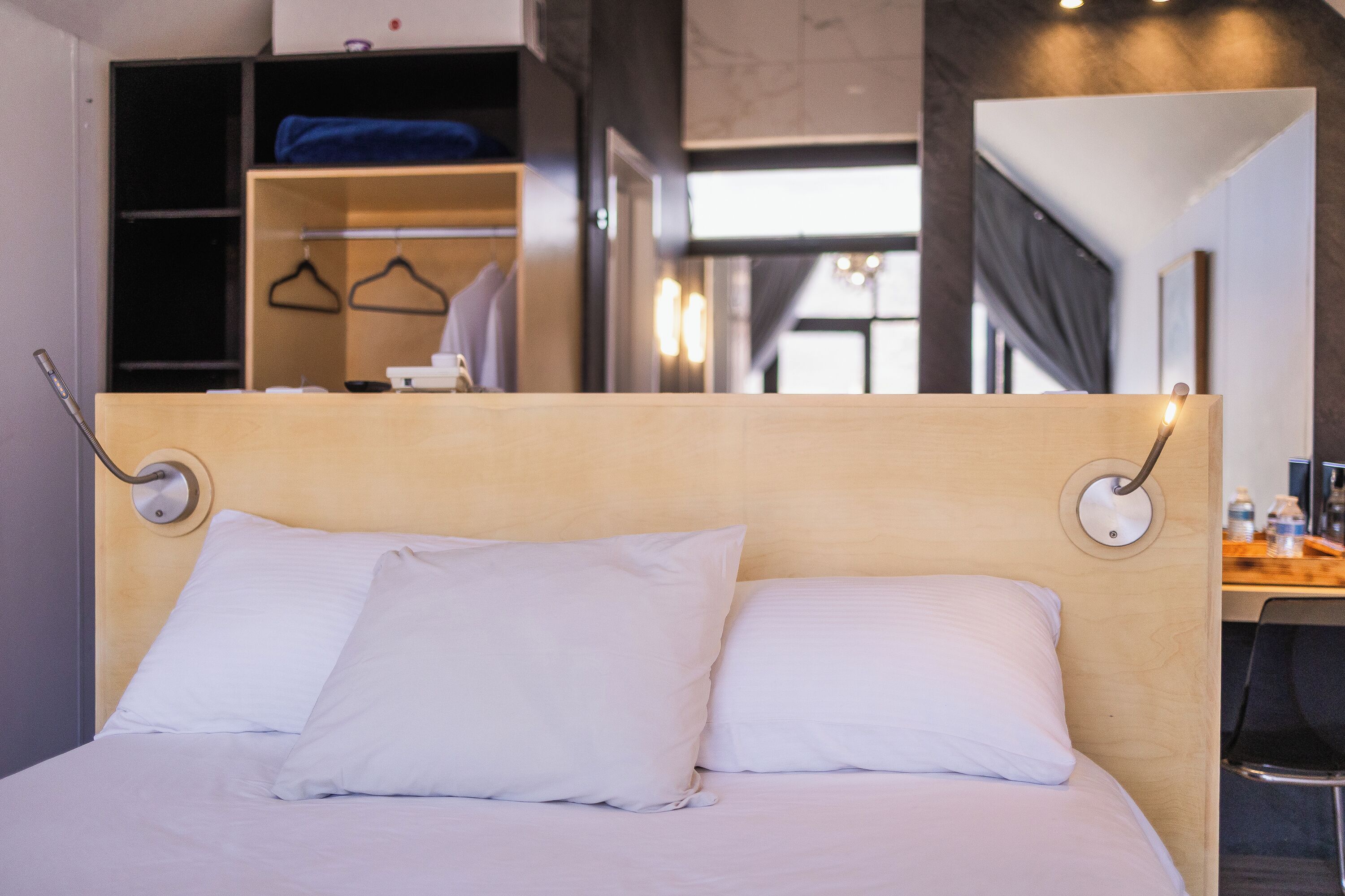 A neatly made bed with white linens, a wooden headboard, and bedside lamps.