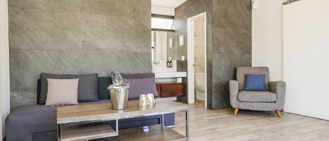 A modern living room with a grey sofa, a wooden coffee table, and a grey armchair.