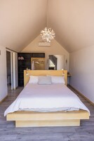 Un dormitorio con una cama grande, cabecera de madera, lámpara colgante y un armario con estantes.