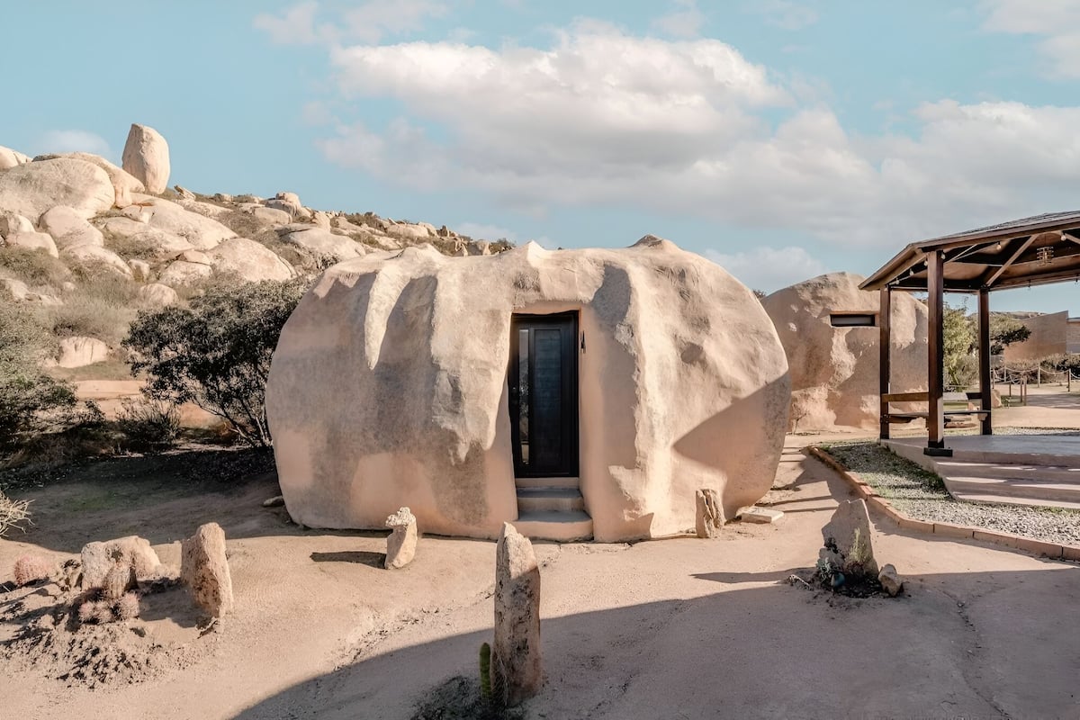A spherical, cave-like structure with a door, surrounded by desert terrain and sparse vegetation.