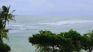 A view of the ocean with waves and palm trees in the foreground. - Polhena Grand Resort & Banquet (Matara)